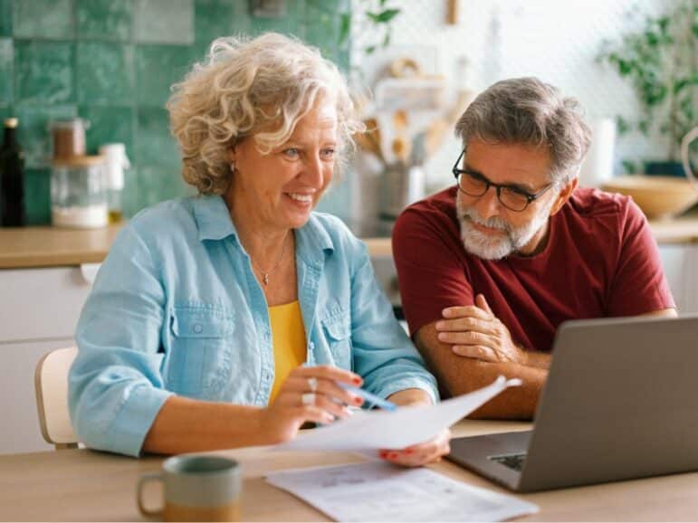 A senior couple looks at finances on a laptop
